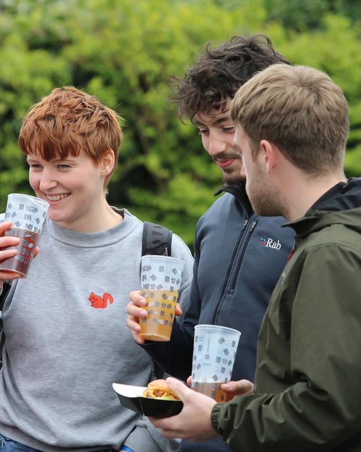 Three friends share a laugh over pints and a burger