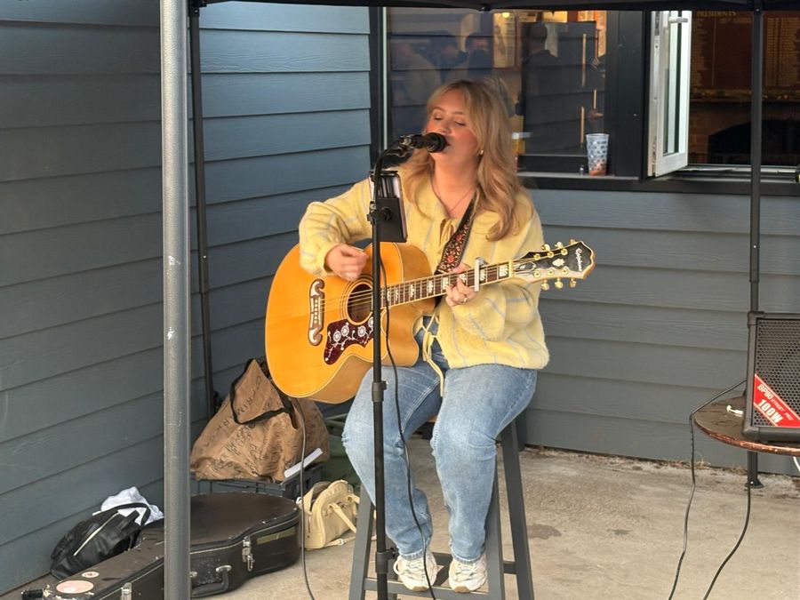 A singer performs an acoustic set with guitar under a gazebo