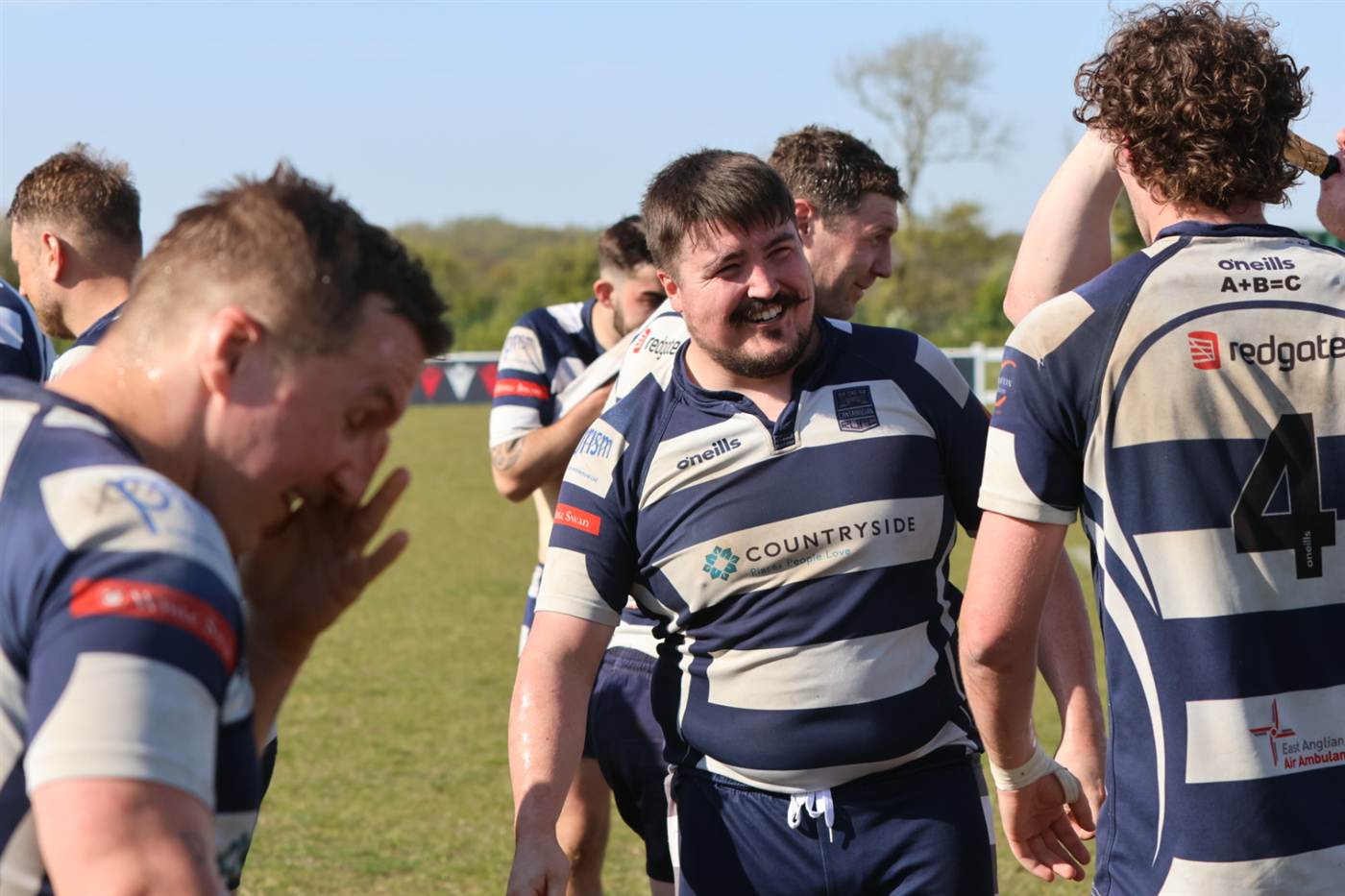 Cantabs players laughing together on the pitch after a match in the sunshine